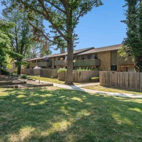 a building with a fence and trees in the front